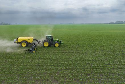 A tractor spreading artificial fertiliser on a corn field